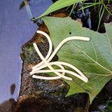 Pond Pro Sqworms on a wet rock on a large green leaf next to water.