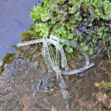 Pond Pro Silver Flake Sqworms on a rock with foliage with water in the background.