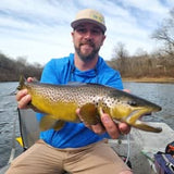 Tim Shannon, holding a large trout on a boat on the Norfork River.