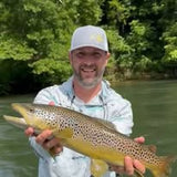 Pond Pro Guide on the Norfork River, holding a large trout.