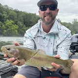 Pond Pro Guide, Tim Shannon, holding a large trout while on a boat on the Norfork River.