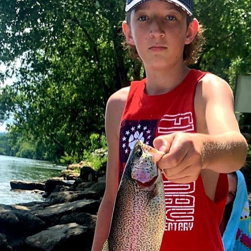 A young boy display the fish he caught at the river with Pond Pro Tim Shannon.