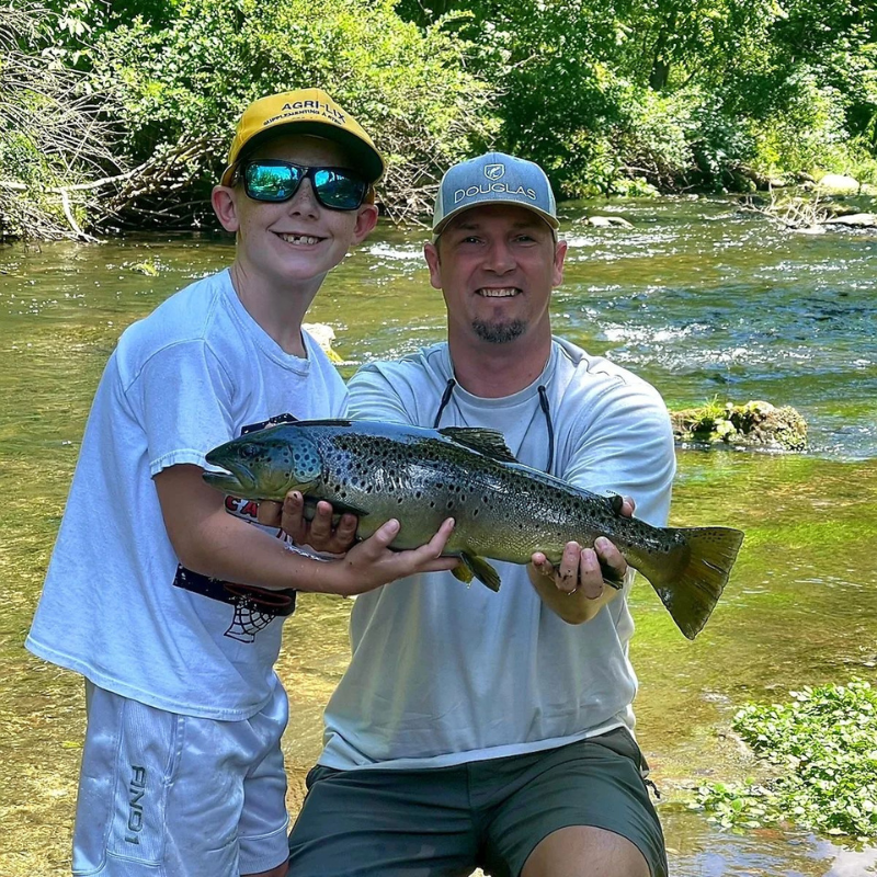 A young boy helping Pond Pro Guide Tim Shannon hold the fish he caught at Dry Run Creek in Arkansas.