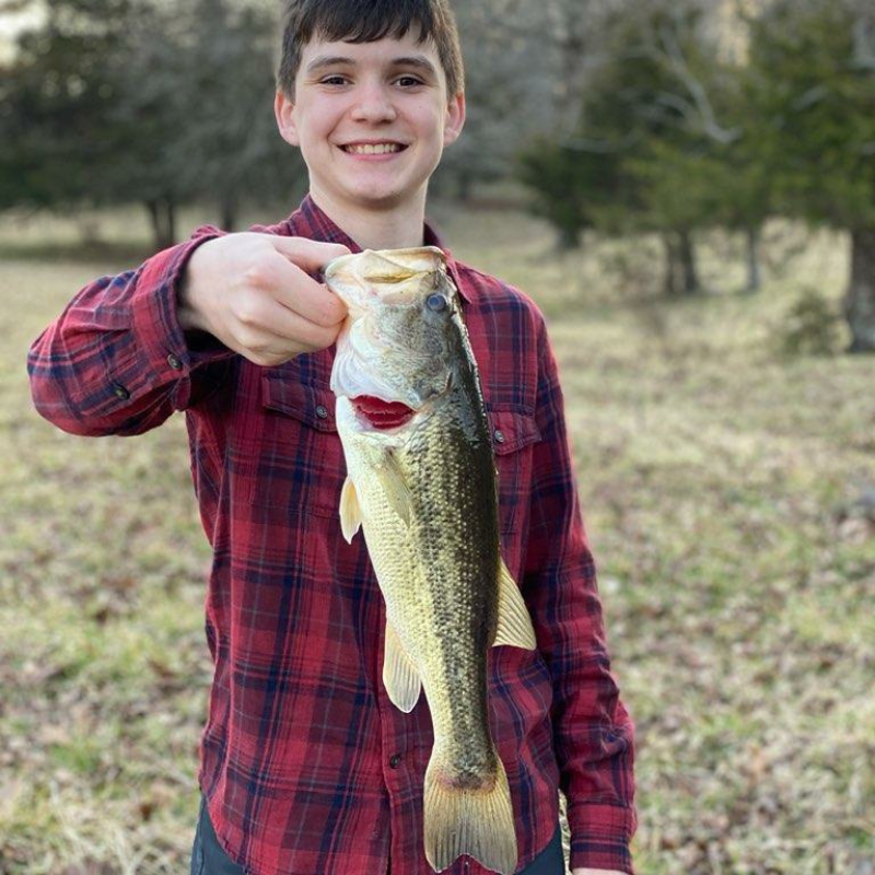 A young boy proudly holding up the bass he caught with the Pond Pros.