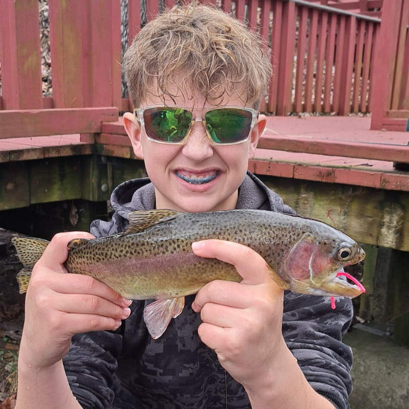 Boy holding a trout with a Pond Pro Bubble Gum Pink Sqworm in its mouth.