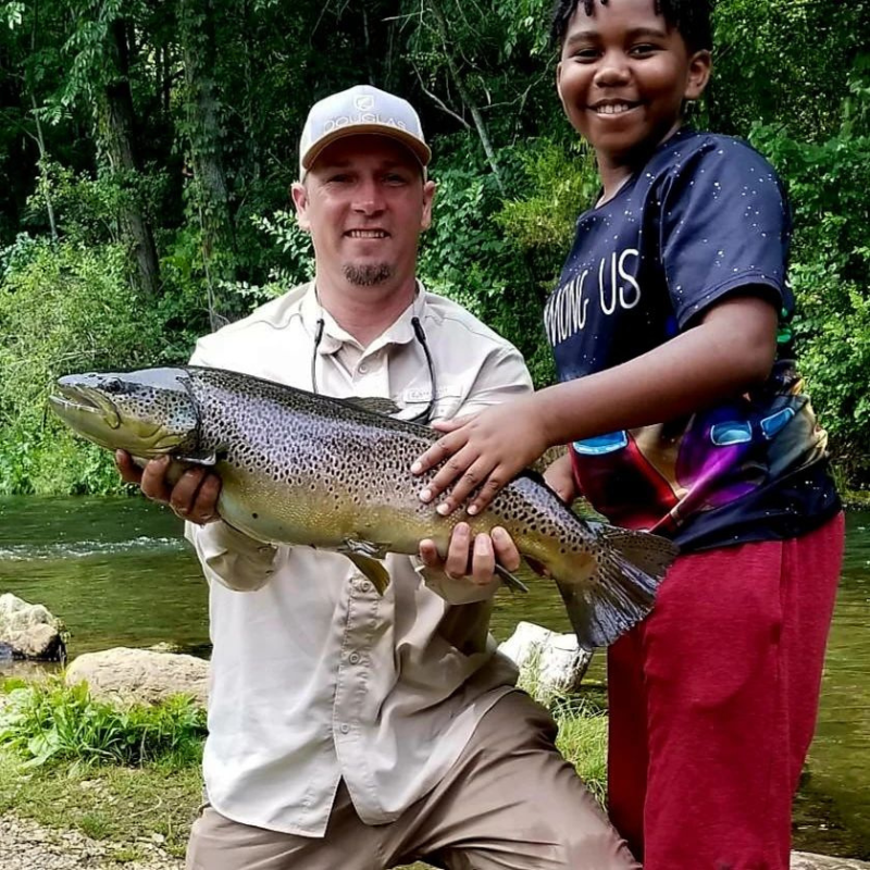 Pond Pro Guide Tim Shannon and boy holding a large trout at Dry Run Creek in Arkansas.