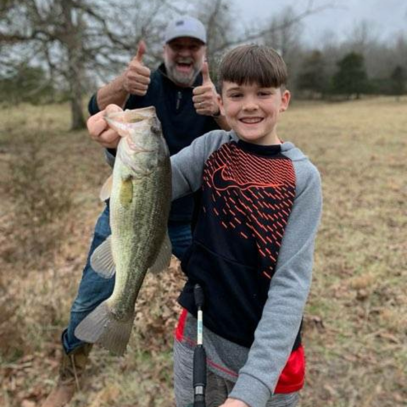 Pond Pro Michael Willett with boy holding large bass while fishing.