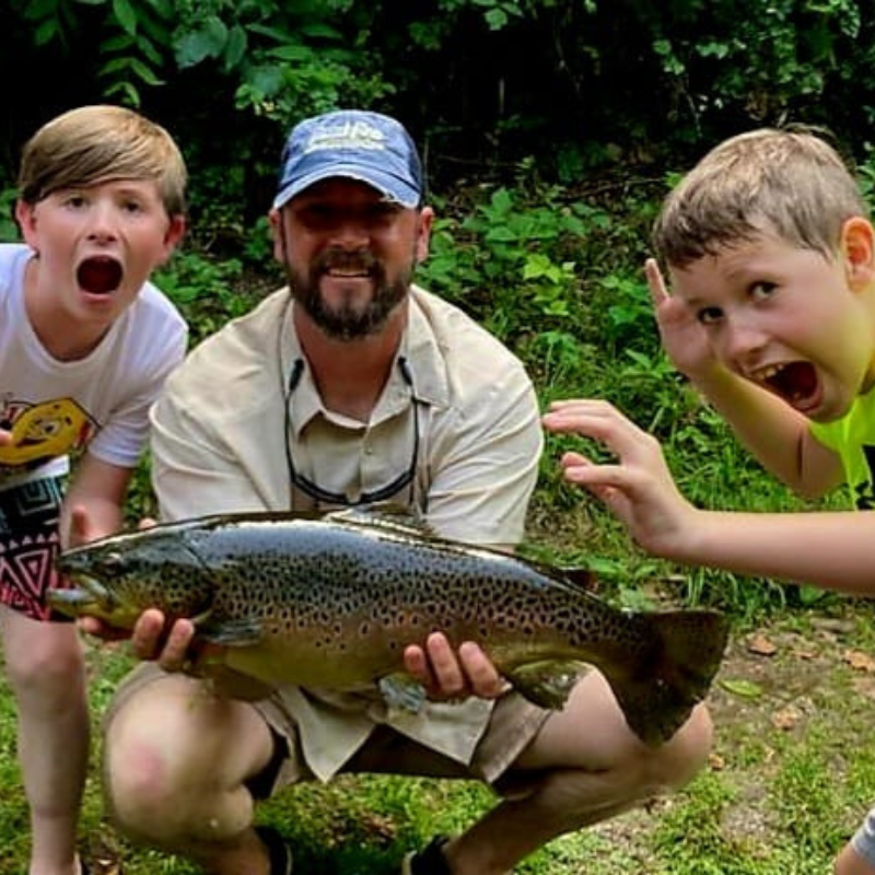 Pond Pro Tim Shannon with son and nephew holding a large trout at Dry Run Creek in Arkansas.