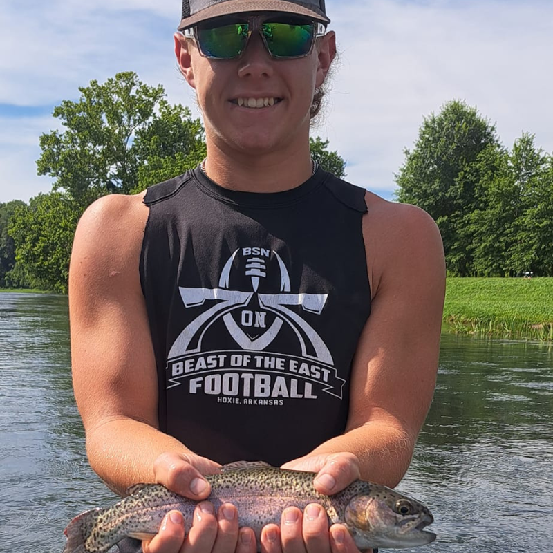 Young boy holding a fish in the river while with Pond Pro Tim Shannon.