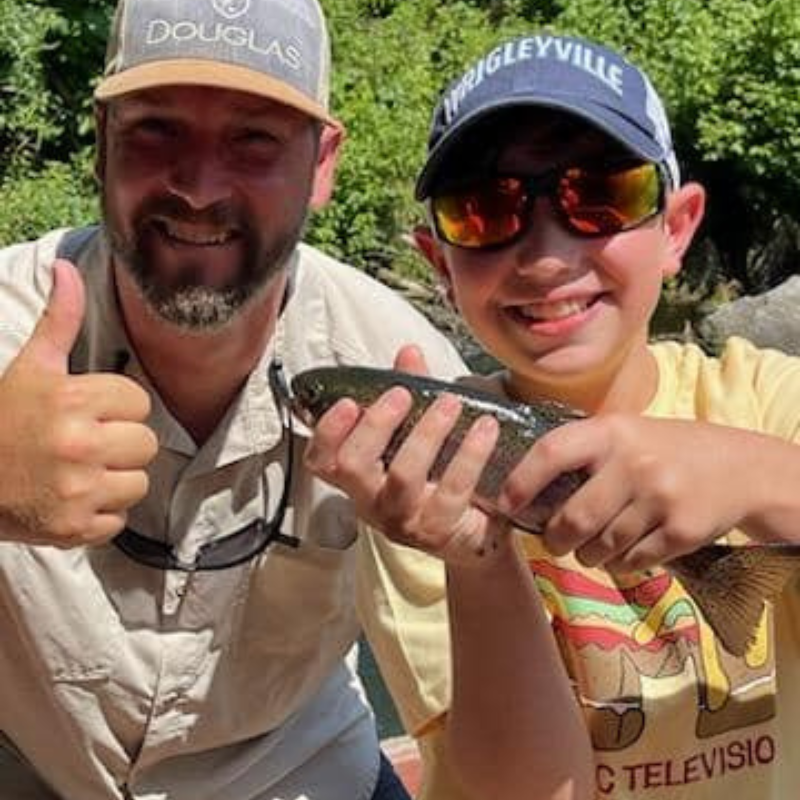 Young boy with Pond Pro Tim Shannon on a guide trip, holding a trout.