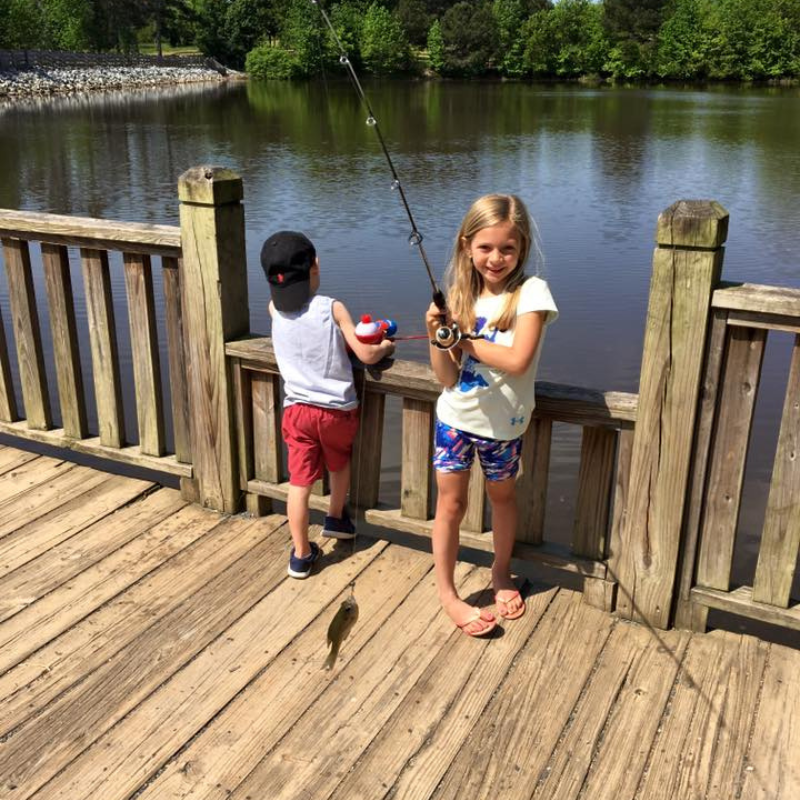 Young girl who caught a fish with her fishing pole off the dock.