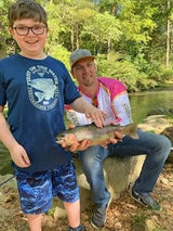A young boy excited to show the trout he caught at Dry Run Creek in Arkansas with Pond Pro, Tim Shannon.