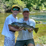 Young boy who caught a large trout at Dry Run Creek in Arkansas, helping Pond Pro, Tim Shannon, hold the fish.