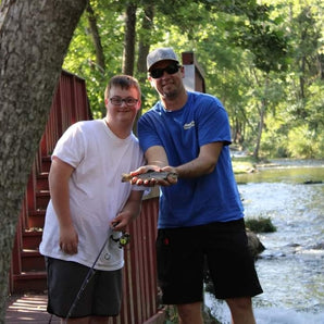 A child standing next to Pond Pro, Tim Shannon, holding a fish caught on Dry Run Creek in Arkansas.