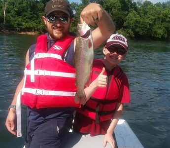Father and Son holding a fish while on a boat in the river