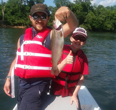 Father and Son holding a fish while on a boat in the river