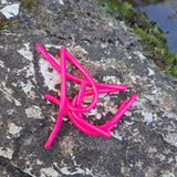 Pond Pro Sqworms in the color Taney Pink on a rock with moss and water in the background.