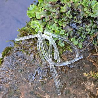Pond Pro Silver Flake Sqworms on a rock with foliage with water in the background.