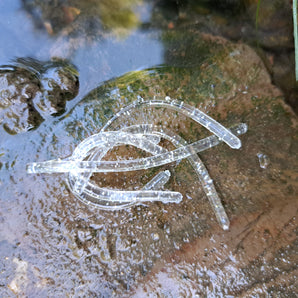 Translucent Pond Pro Silver Flake Sqworms on a rock with water.