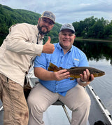 Pond Pro Guide, Tim Shannon, with a man holding a trout, in a boat, on the White River in Arkansas.