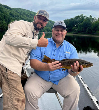 Pond Pro Guide, Tim Shannon, with a man holding a trout, in a boat, on the White River in Arkansas.