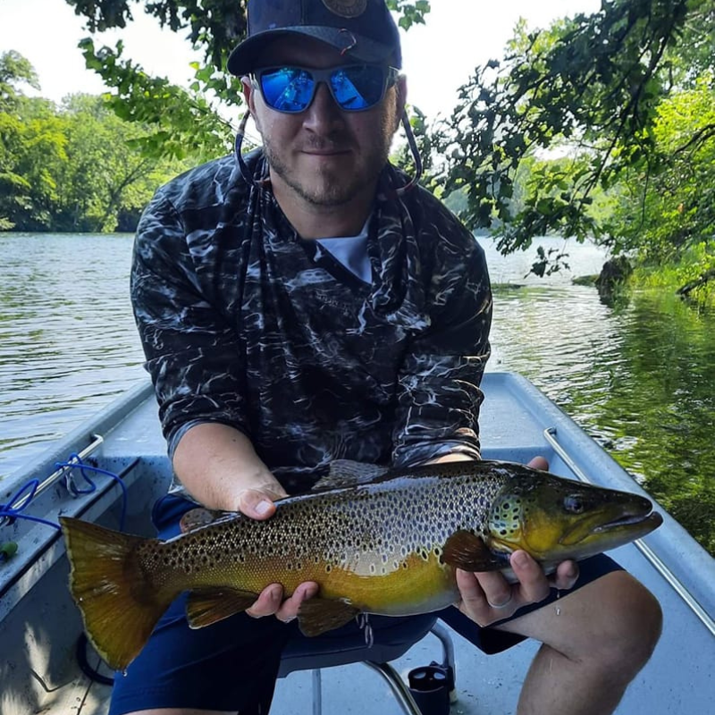 Man holding a large fish on a boat with a natural background