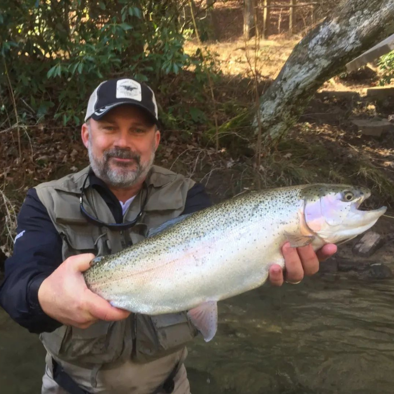 Man holding large fish while in the river. 